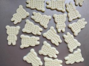 取一块面团，擀成厚约2毫米的薄片，用模具刻出小熊的图案，表面用叉子扎一些小孔，以免烘烤的时候中间鼓起变形。