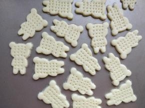 取一块面团，擀成厚约2毫米的薄片，用模具刻出小熊的图案，表面用叉子扎一些小孔，以免烘烤的时候中间鼓起变形。