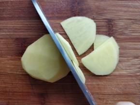 将土豆洗净，刮皮，用刀从中间切开，然后把切口朝下，用刀切成2-3毫米厚的片。土豆片不要切得太薄，口感不好而且熟了容易碎。