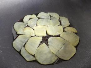 在平底不粘锅中倒少许油，小火加热，将土豆片摊平在锅中。