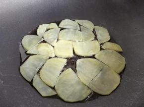 在平底不粘锅中倒少许油，小火加热，将土豆片摊平在锅中。