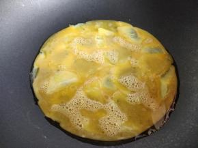 将蛋液浇一半在土豆片上，轻轻晃动锅，让蛋液摊平