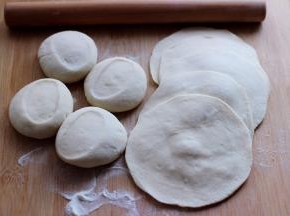 醒发好的面团排气揉匀后，用手搓成长条后，用刀切成大小一致的剂子，擀成圆形薄面皮。