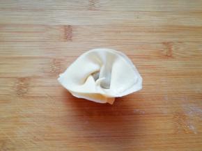 然后把两头折回来捏紧(怕粘的不紧可以沾点水)，一个馄饨就包好了。