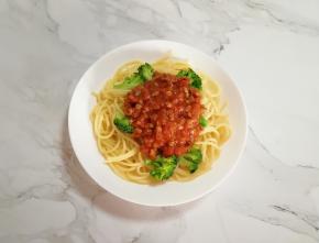 煮好的意面和西兰花一起盛在盘子里，浇上做好的肉酱。