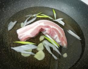 五花肉凉水入锅，放葱和姜，加入一勺料酒烧开焯水。