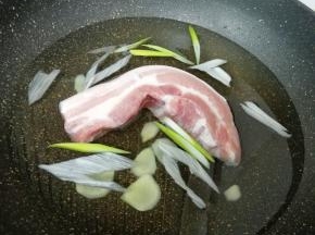 五花肉凉水入锅，放葱和姜，加入一勺料酒烧开焯水。