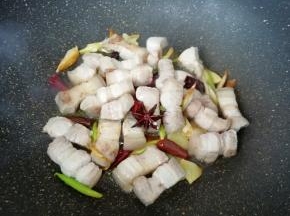 下入五花肉煸炒至出油。