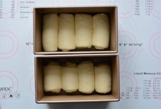 把卷好的面团排入土司盒中。