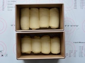 把卷好的面团排入土司盒中。