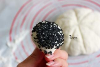 小面团排气，滚圆，蘸上黑芝麻，蘸点水，让黑芝麻均匀粘在面团上。