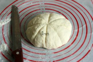 把面团压平排气，揉成光滑的面团，晒上面粉，用刀背在面团上压出印痕，均匀分成8等分。