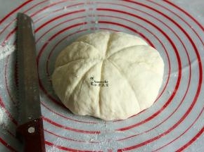 把面团压平排气，揉成光滑的面团，晒上面粉，用刀背在面团上压出印痕，均匀分成8等分。
