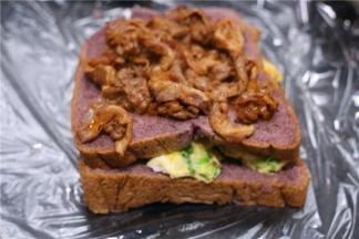 把吐司放保鲜膜上，吐司上铺炒好的鸡蛋，盖上一片吐司，再铺上煎好的肉，上面再铺上一片吐司。最后用保鲜膜裹紧。