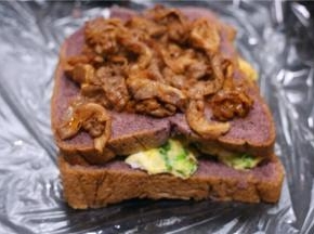 把吐司放保鲜膜上，吐司上铺炒好的鸡蛋，盖上一片吐司，再铺上煎好的肉，上面再铺上一片吐司。最后用保鲜膜裹紧。