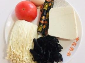 准备好所需的食材：

嫩豆腐1块，火腿肠2根，西红柿1个，鸡蛋1个，木耳提前泡发好，金针菇200克。