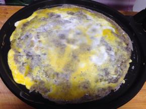 
磕入一个鸡蛋，用刮子迅速刮平