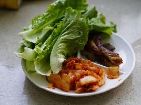 开一包泡菜，再将烤肉切好，将洗好的生菜控好水搭配在一起。