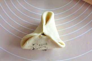 将右半部分的面皮推到左边捏合住，将三面全捏紧，就可以形成三角状了。