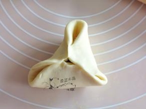 将右半部分的面皮推到左边捏合住，将三面全捏紧，就可以形成三角状了。