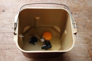 将水、鸡蛋倒入面包桶中，盐、糖对角放，黑芝麻酱放中间；