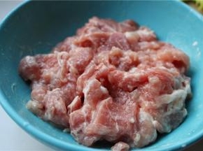 制作面条的时候，开始准备焖面的配菜。先把里脊肉切成片，加入水淀粉、少许盐和一勺油，拌匀腌制10分钟，这样炒出来的肉口感会特别嫩，而且炒多久也不会老。