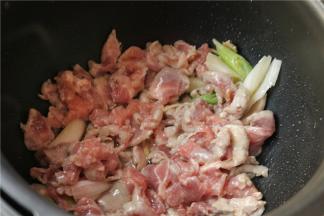 压力锅打开盖子，用开盖收汁功能，锅胆热了之后，加入比炒菜略微多一点的花生油，然后下入腌制好的肉片和葱姜丝滑炒，至肉片变色，葱姜的香味散发出来。
