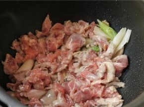 压力锅打开盖子，用开盖收汁功能，锅胆热了之后，加入比炒菜略微多一点的花生油，然后下入腌制好的肉片和葱姜丝滑炒，至肉片变色，葱姜的香味散发出来。