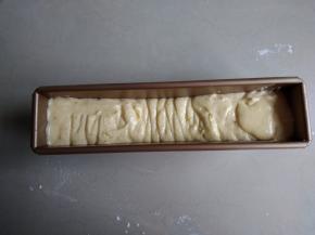 将蛋糕糊挤入到长条磅蛋糕模具中（我的模具尺寸是230*50*65MM），两边高，中间低，在桌面上震几下