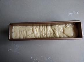 将蛋糕糊挤入到长条磅蛋糕模具中（我的模具尺寸是230*50*65MM），两边高，中间低，在桌面上震几下