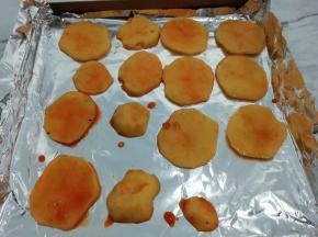 取一个烤盘铺上锡纸，把腌制好的土豆片码在烤盘上