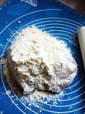 面团放案板上，加入面粉用力揉搓。