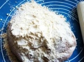 面团放案板上，加入面粉用力揉搓。