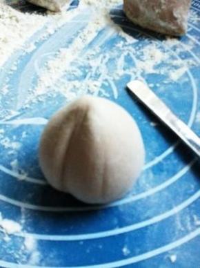 双手转动面团，将馒头捏成桃子形状，用勺子的把压出桃子的中间的痕。