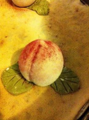 桃子和叶子组合在一起。用干毛刷沾一点红曲粉轻轻地刷在桃嘴部分。因为有厨友问如何才能刷的好看，这里特别补充说明一下。用毛刷沾干粉从桃嘴由下往上刷，最后用刷子轻轻在桃嘴部分点动，使粉从刷毛自然流下。如果想小清新一点，可以在红曲粉中混入一点点，注意是一点点面粉，效果会更自然一点。