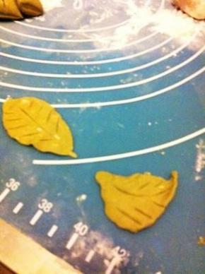 取一点绿面团随意做成叶子形状，用勺把压出叶痕。