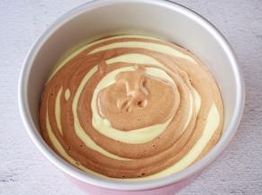 就这样一勺原味一勺可可，直至所有的蛋糕糊用完，端起模具的两端，轻轻震几下，震出大气泡