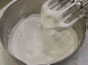 糖浆呈细线状倒入蛋白内，一边倒入一边打发，打蛋头提起呈鹰嘴状。