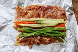 腌制入味的鸡腿肉，铺在锡纸上，锡纸大一些，亚光面接触食物。把切好的蔬菜条摆在上面，如果鸡肉有不平整的地方，可以用刀切割下来补在肉少的地方。