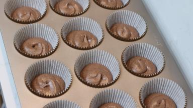 13.	将面糊装入裱花袋中。先在杯子蛋糕纸托中挤一层面糊