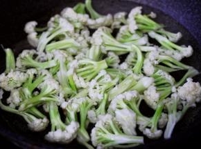 菜花用手撕成小块状，锅中倒入适量的清水烧开后，放入一勺盐后把菜花进行焯水备用。