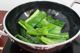 热锅，倒入适量的食用油，改为大火，把腌制好的尖椒放入锅里。然后撒点盐，用锅铲不断搓辣椒，有盐有助于辣椒容易搓起虎皮，然后出锅。