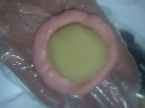 取一个水油皮按扁圆(中间厚周边薄)，包入油酥