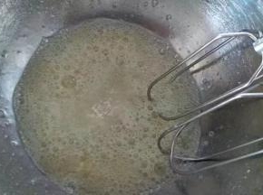 用电动打蛋器进行低速打发至鱼眼泡状态，加入余下35克糖的三分之一，再进行低速打发