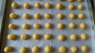 把面团分成10克一个，搓成小圆球，（此时开始预热烤箱）整齐的摆在烤盘内，然后用拇指按个小窝