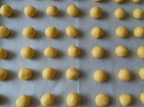 把面团分成10克一个，搓成小圆球，（此时开始预热烤箱）整齐的摆在烤盘内，然后用拇指按个小窝