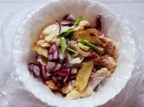 取一个大碗，碗里放入一个塑料袋，把鸡根放入塑料袋，加葱、姜、洋葱、胡椒粉、料酒。