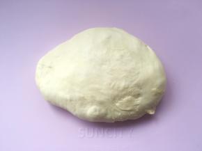 将发酵好的面团倒在揉面垫上，用手掌按压排气；