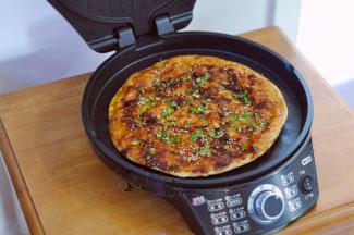 将饼翻面，继续加热几分钟。煎至两面金黄，然后表面刷上酱，撒上葱花和白芝麻即可。