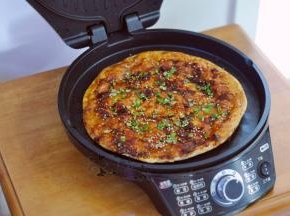 将饼翻面，继续加热几分钟。煎至两面金黄，然后表面刷上酱，撒上葱花和白芝麻即可。